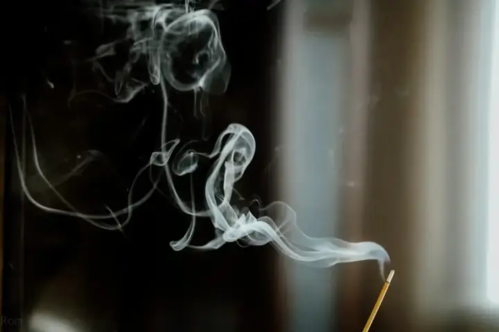 Incense smoke rising gently in temple light